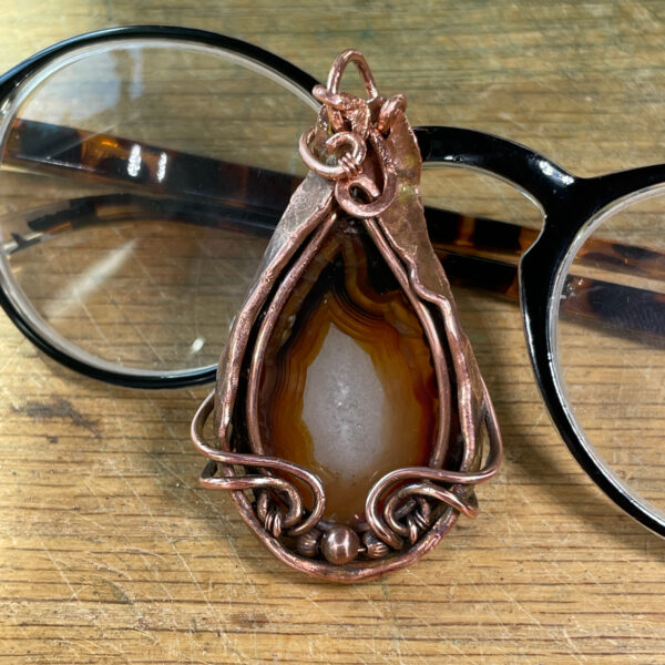 Fortification Agate pendant in tones of brown with copper frame.