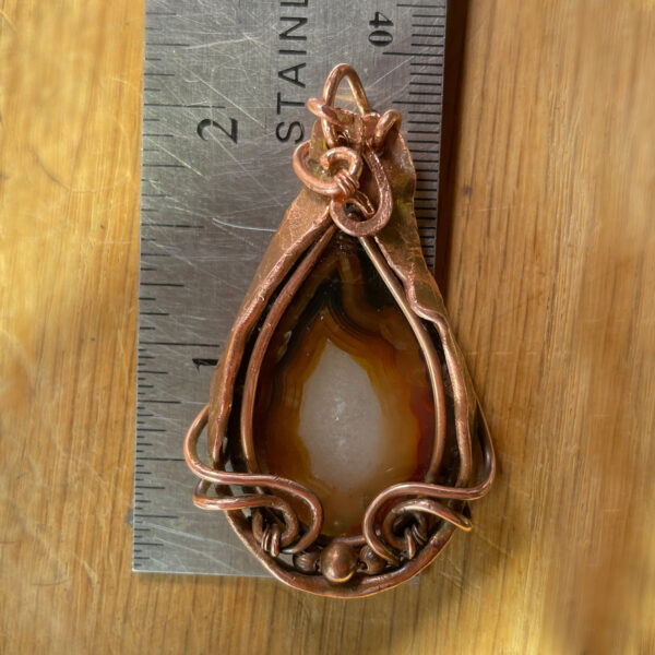 Fortification Agate pendant in tones of brown with copper frame.