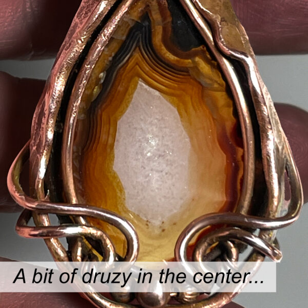 Fortification Agate pendant in tones of brown with copper frame.