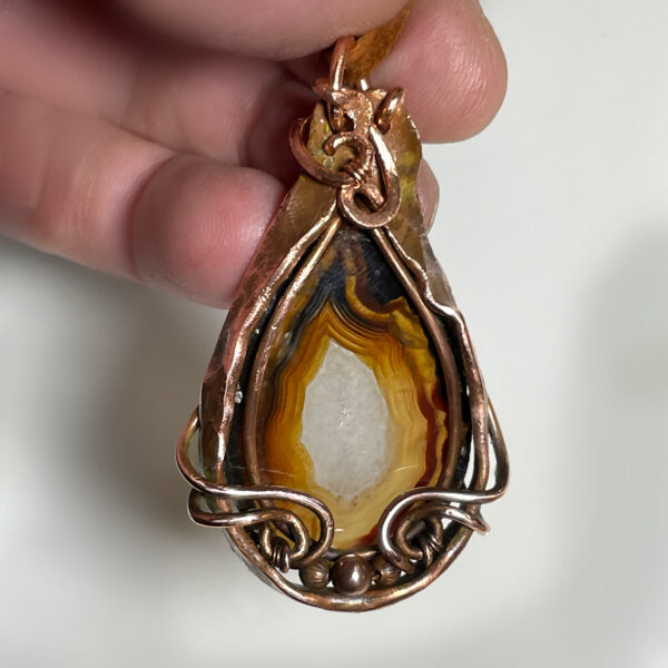 Fortification Agate pendant in tones of brown with copper frame.